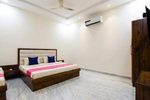 a bedroom with a bed with blue and pink pillows at Hotel Savera Amritsar Near Golden Temple in Amritsar