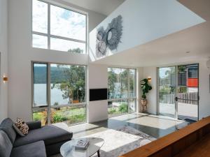 a living room with white walls and large windows at Tasman Tides - Architecturally-designed holiday home in Eaglehawk Neck