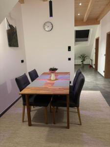 a dining room table with chairs and a clock on the wall at Ferienwohnung Abendrot Jochner in Aidling +3 photos