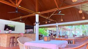 a restaurant with tables and chairs and a tv at Kamala Garden Bungalows in Kamala Beach