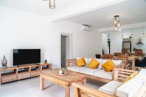 a living room with a couch and a tv at Mango House - 2 Bedrooms & Private Pool in La Gaulette