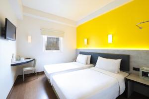 two beds in a room with a yellow wall at Amaris Hotel Bekasi Barat in Bekasi