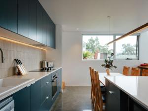 a kitchen with black cabinets and a white counter top at Tasman Tides - Architecturally-designed holiday home in Eaglehawk Neck +28 photos