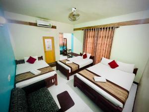 a hotel room with two beds and a chair at Cinnamon Tree Tourist Rest in Anuradhapura