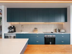 a kitchen with blue cabinets and a sink at Tasman Tides - Architecturally-designed holiday home in Eaglehawk Neck