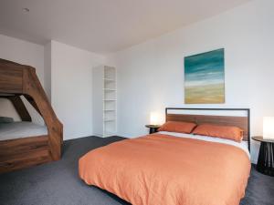 a bedroom with an orange bed and two lamps at Tasman Tides - Architecturally-designed holiday home in Eaglehawk Neck