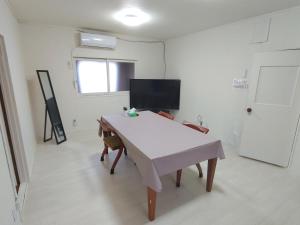 a room with a white table and a tv at OZigaoka Guest House in Otsu