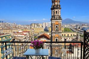 a clock tower with a table with flowers on a balcony at La Casa di Giorgio Panoramic Rooms in Naples