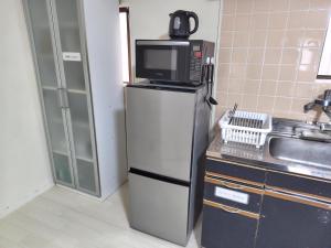 a microwave on top of a refrigerator in a kitchen at OZigaoka Guest House in Otsu