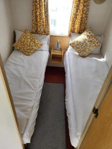 two beds in a small room with a window at Caravan in Chapel Skegness in Chapel Saint Leonards