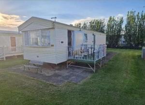 a small white house with a dog on a porch at Caravan in Chapel Skegness in Chapel Saint Leonards