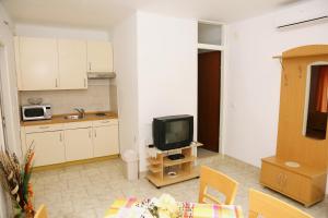 ein Wohnzimmer mit einem TV und einer Küche in der Unterkunft Apartment Brna 1 in Brna