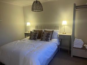 a bedroom with a white bed with two tables and two lamps at Brocklamont cottage in Ballymena