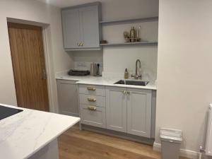 a kitchen with white cabinets and a sink at Brocklamont cottage in Ballymena