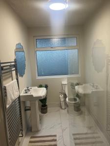 a bathroom with two sinks and a toilet and a window at Brocklamont cottage in Ballymena +4 photos