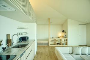 a kitchen and living room with a couch and a sink at Hiire IZU FUTO in Ito