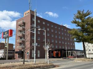 a large red brick building on a street corner at APA Hotel Okhotsk Kitami in Kitami