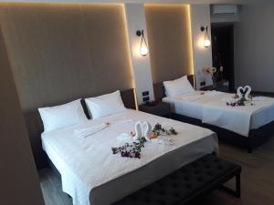zwei Betten in einem Hotelzimmer mit Blumen darauf in der Unterkunft Evdirhan Otel in Dosemealti