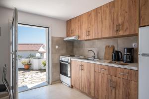a kitchen with wooden cabinets and a stove at Katerina Horizon Apartments by Konnect - 1,8km from Ipsos beach in Ipsos
