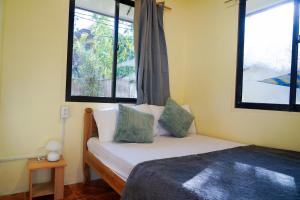 a bedroom with a bed and two windows at Aman House in San Vicente