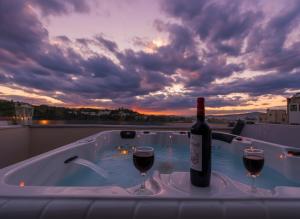 a bottle of wine and two wine glasses in a hot tub at Lotus Center Inn in Athens