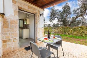 an outdoor patio with a table and chairs and a kitchen at Trulli degli Augelli by BarbarHouse in San Michele Salentino