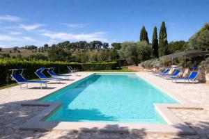 a swimming pool with blue chairs and a swimming poolvisor at Scappo in Umbria, La dolce Godera in Lugnano in Teverina