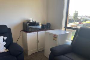 a room with a tv and two chairs and a microwave at Spacious Private 4BR Upper Floor Sleeps 8 Spa Free parking in Werribee