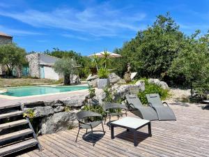 a deck with chairs and a table next to a pool at Les Dolines in Balazuc +13 photos
