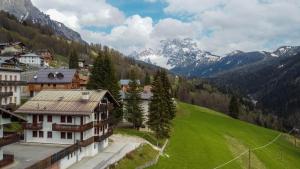 a village in the mountains with a green field at Appartamento Mondeval in Selva di Cadore