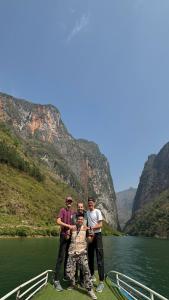 a group of three men standing on a boat on a river at Ha Giang SkyPath Hostel & Tours in Làng Lap