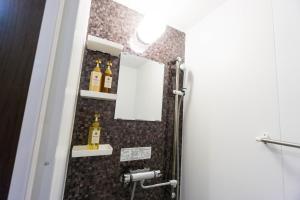 a bathroom with a mirror and some bottles on the wall at コンドミニオ久貝 in Miyako-jima
