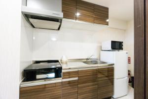 a small kitchen with a sink and a refrigerator at コンドミニオ久貝 in Miyako-jima