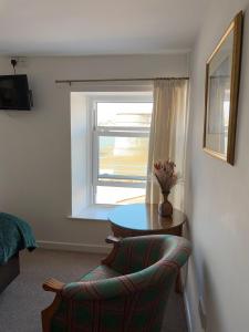a room with a table and a chair and a window at Shipwright Inn in Pembroke Dock