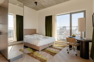 a bedroom with a bed and a desk and windows at Makerstoren Short stay serviced apartments for 28 to 180 days in Amsterdam +23 photos