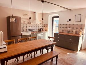 a kitchen with a wooden table and a dining room at La Bastide des Dentelles in Roaix