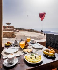 a table with food and drinks and a view of the ocean at Le Nid d'Aigle in Mirleft