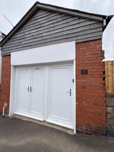 two white garage doors on a brick building at The old surgery in Rhymney