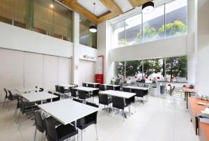 a dining room with tables and chairs and windows at Amaris Hotel Bekasi Barat in Bekasi