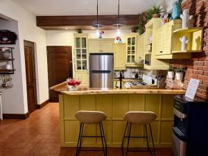 a kitchen with yellow cabinets and a counter with stools at Casa Del Cielo in Jarabacoa