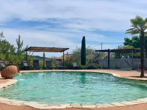 a swimming pool in a yard with chairs and a gazebo at Au Pays de Cocagne in Nyons