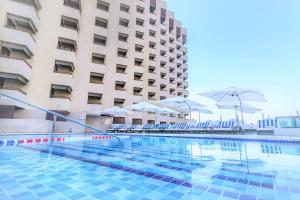 a swimming pool with chairs and umbrellas in front of a building at Radisson Blu Hotel, Dubai Deira Creek in Dubai