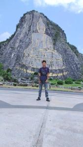 a man standing in front of a large statue at Wai zin in Sara Buri