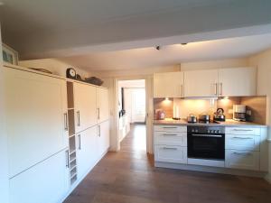 a kitchen with white cabinets and a stove top oven at Uijs Hüs in Borgsum +11 photos