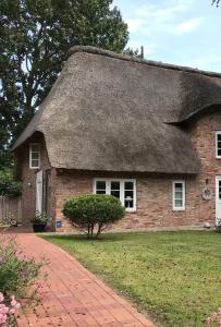 an old brick house with a thatched roof at WattLütt in Oevenum