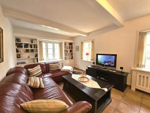 a living room with a leather couch and a television at Ilskes Hus in Oevenum