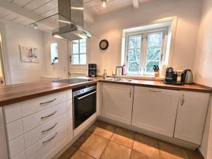 a kitchen with white cabinets and a sink and a window at Ilskes Hus in Oevenum