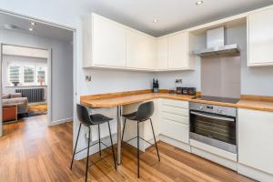 a kitchen with white cabinets and bar stools at The Castle Suite 24h Gym Free Parking in Kenilworth +14 photos