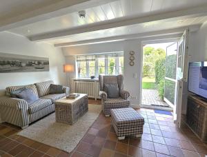 a living room with couches and chairs and a television at Pastoratshof - Haus 6 in Wrixum