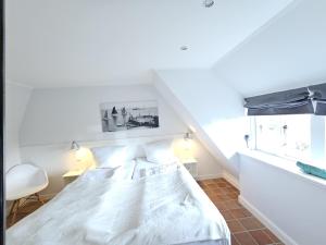 a white bed in a room with a window at Pastoratshof - Haus 6 in Wrixum